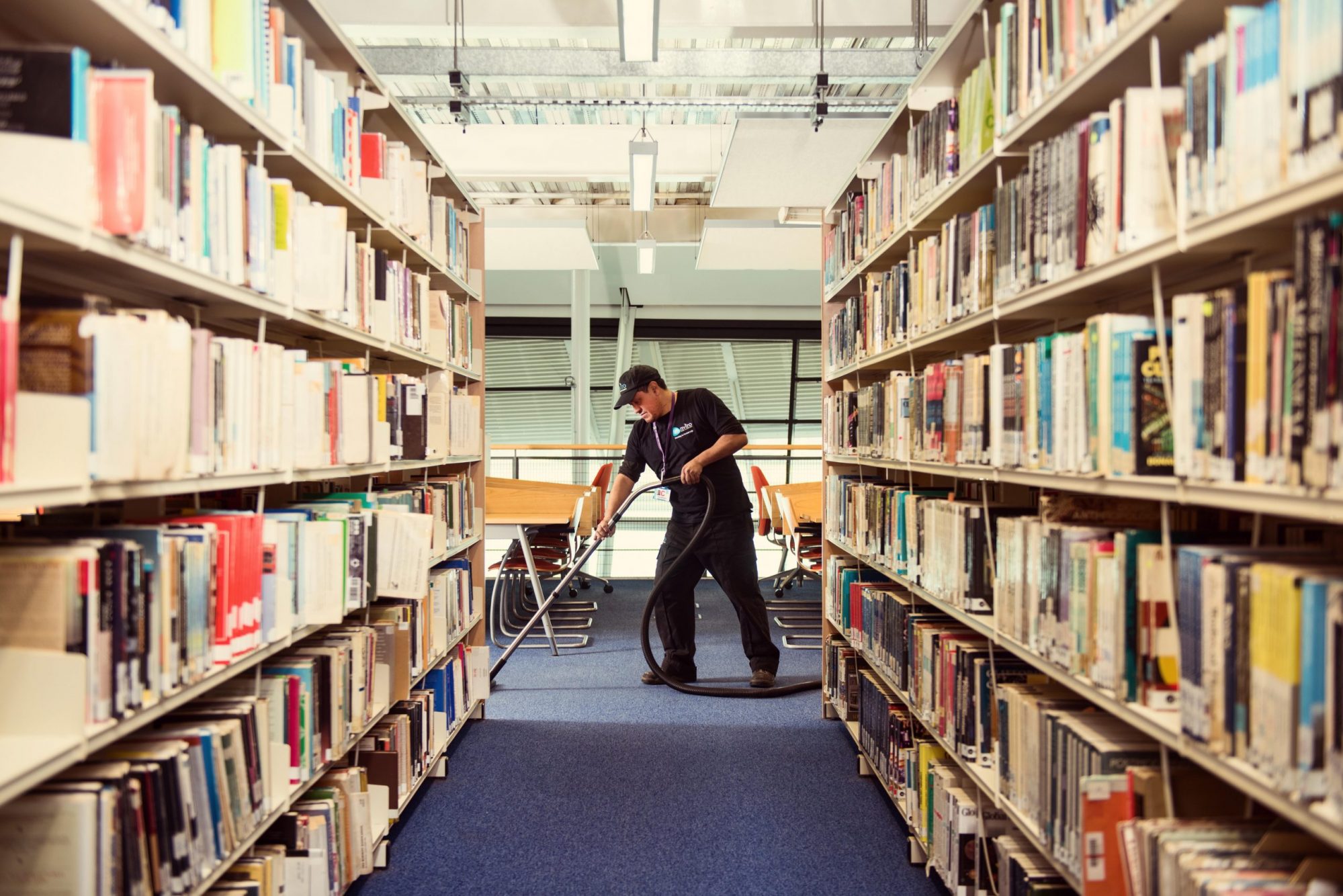Cleaner vacuuming in library